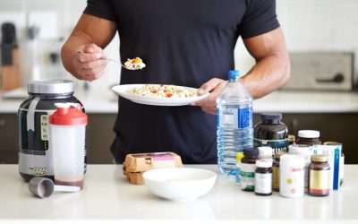 Une variété de suppléments pour la musculation et une assiette de nourriture saine.